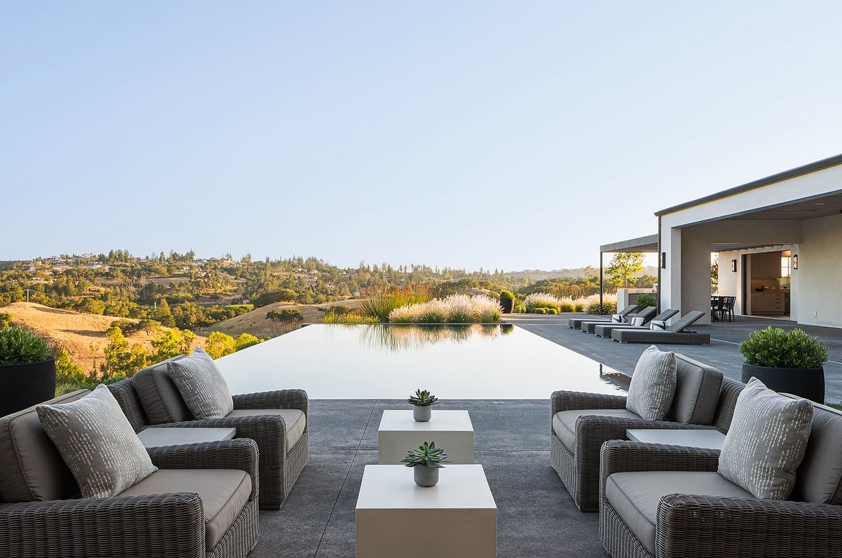 a pool with chairs and a view of the hills