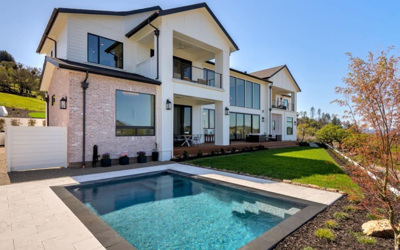 Backyard of modern wine country luxury home with green lawn and refreshing swimming pool.