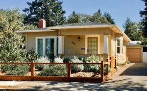 a house with a fence and trees in the background