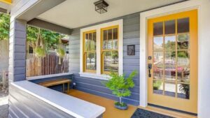 a front porch of a house with yellow doors and a bench